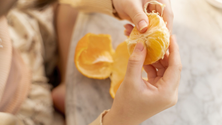 close up of a person holding a peeled orange