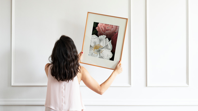 Person hanging framed flower art