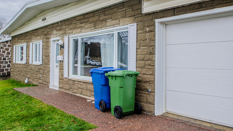 Blue and green garbage bins outside a property