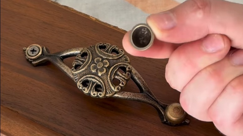 Person applying screw cap to screws on vintage pull
