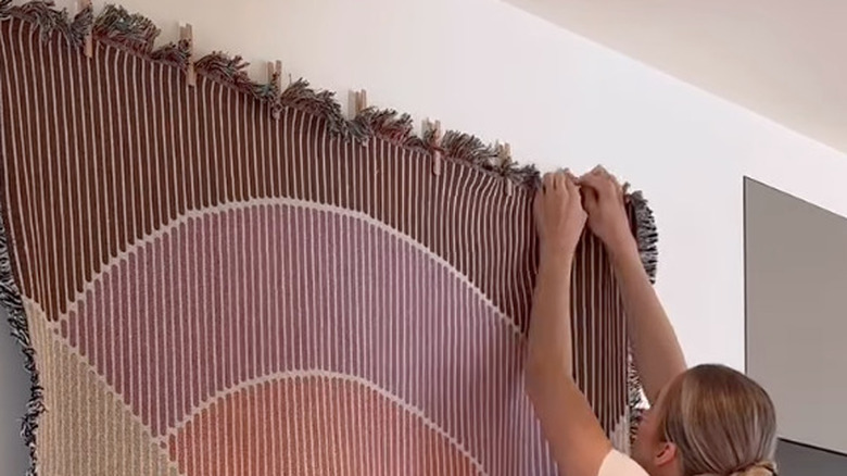 woman hanging tapestry on wall