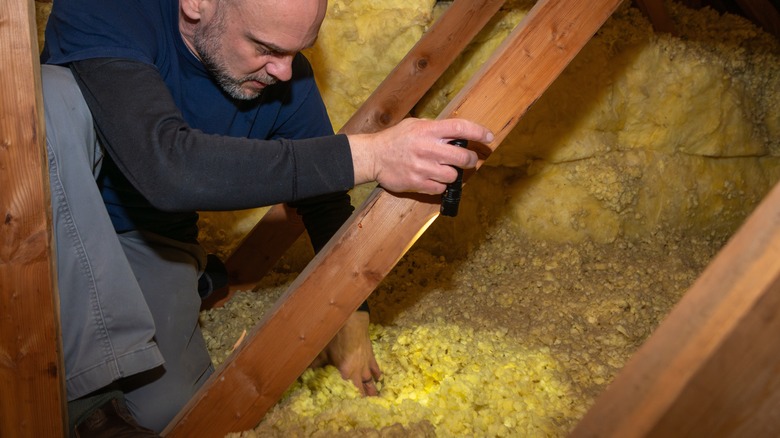A home inspector examining a wooden roof interior structure