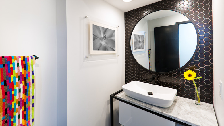 black and white bathroom with colorful towel and flower