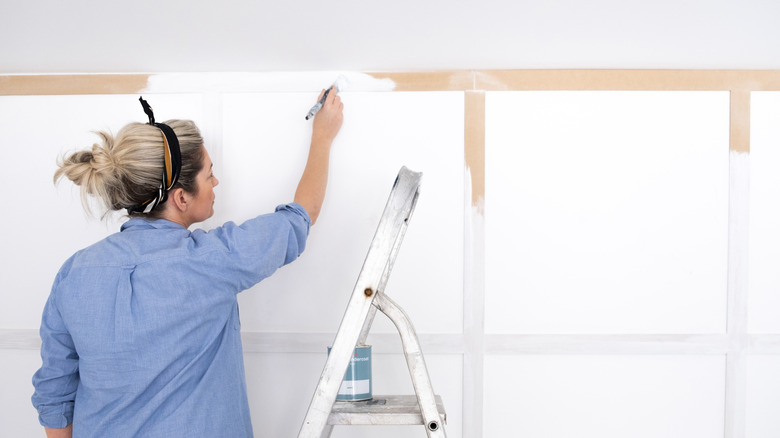 woman painting molding on wall in bright white color