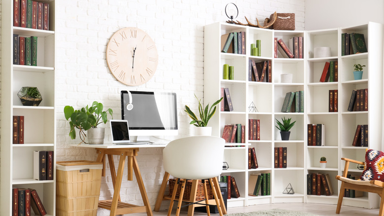 Home office uses the chic cubicle trend by adding in plants and books on white bookshelves