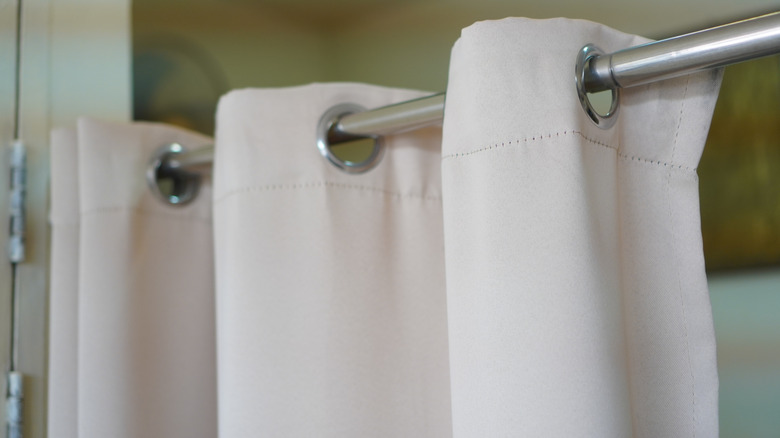Curtain rod with beige blackout curtains.