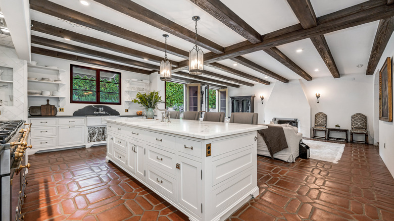 Kitchen with exposed beams, white cabinets, and a brown tile floor