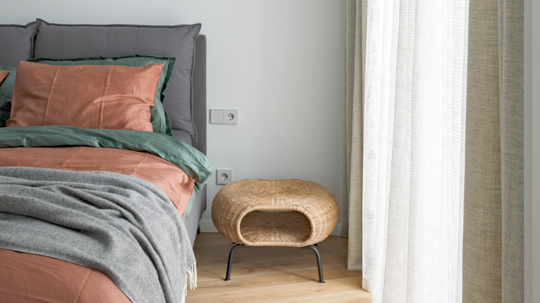A bed flanked by a rounded rattan nightstand