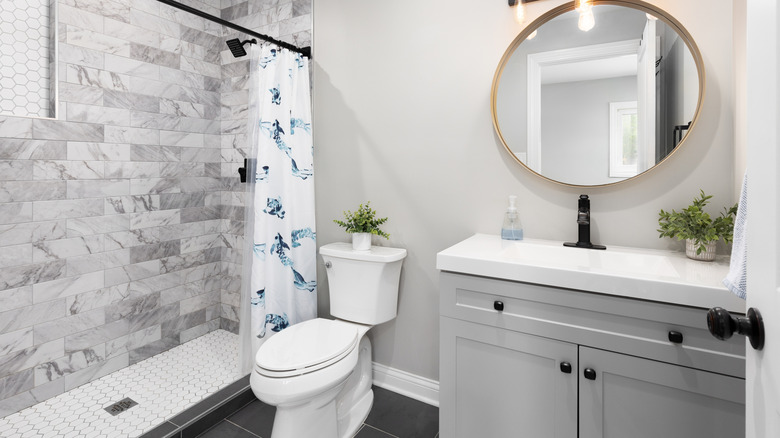 modern bathroom with round vanity mirror and gray cabinet