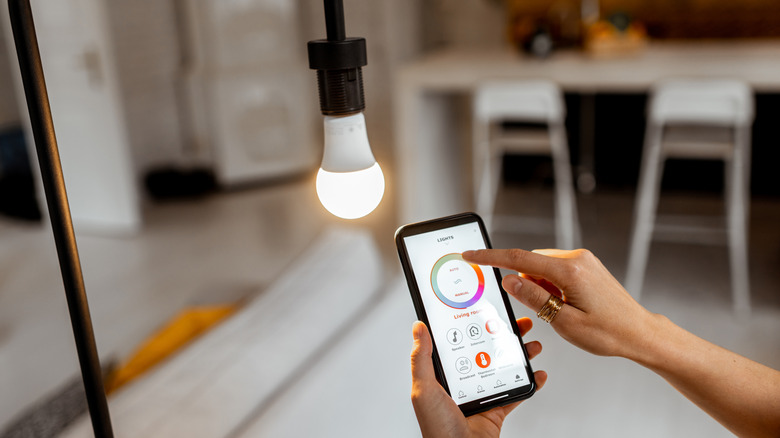 Homeowner using an app to adjust a smart light bulb in a floor lamp