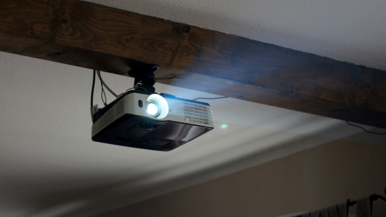 Projector mounted to a beam on the ceiling in a dark room
