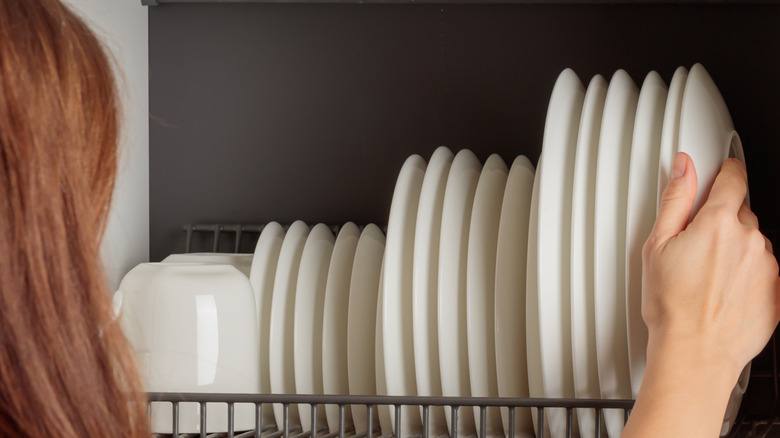 A person grabbing a dish out of a wall-mounted rack