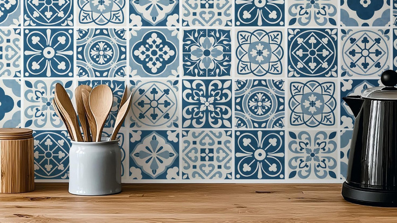 Blue and white tile decals on a backsplash with spoons and a kettle.