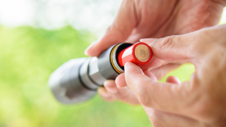 Man inserting batteries into a flashlight