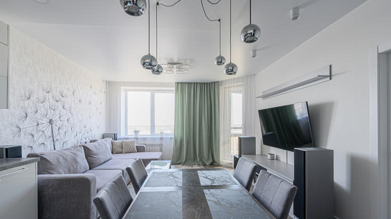 Living and kitchen with chrome hardware and cool tones. Chrome pendant lighting, drawer pulls, and chrome shelf.
