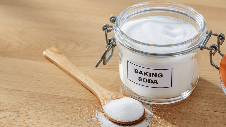 A jar of labeled baking soda with a wooden spoon