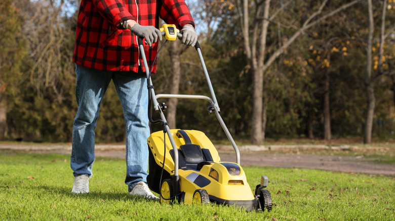 A person pushing a lawn mower outdoors