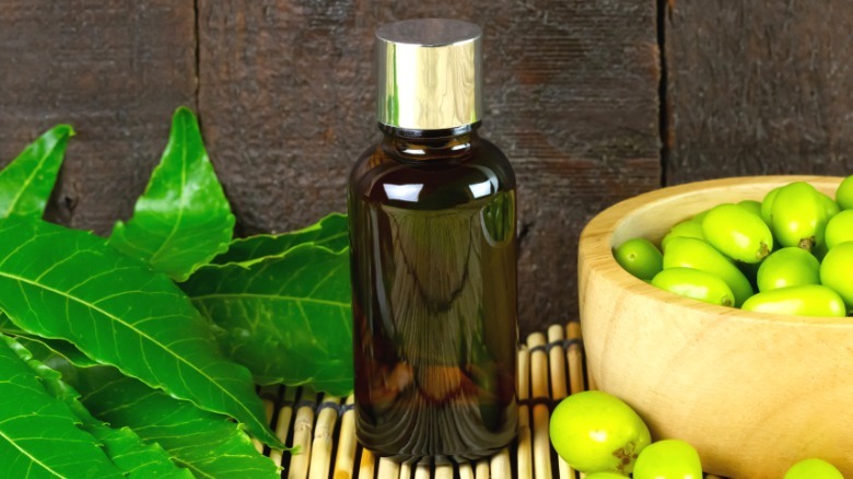 bottle of neem oil on bamboo mat with leaves and fruit