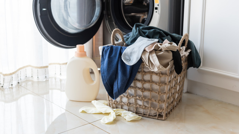 A basket of laundry with detergent in front of a washing machine