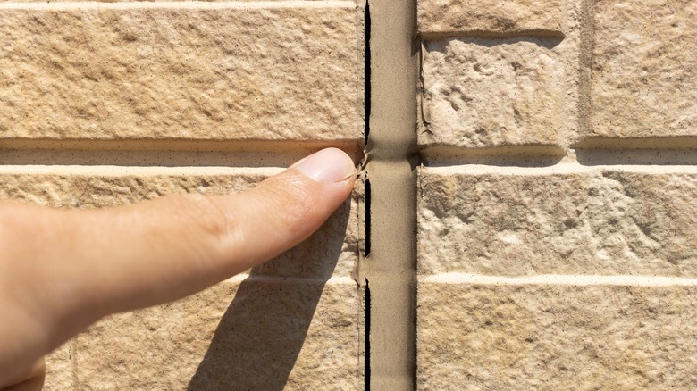 finger pointing at crack in caulk