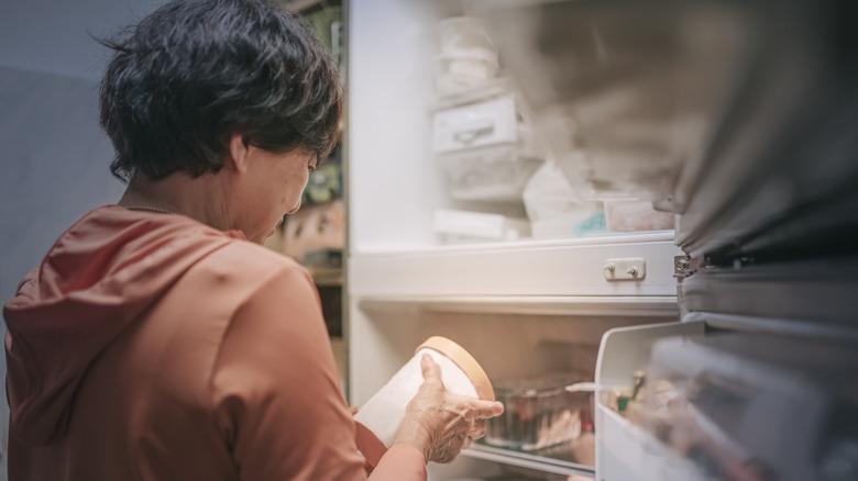 woman holding carton by freezer