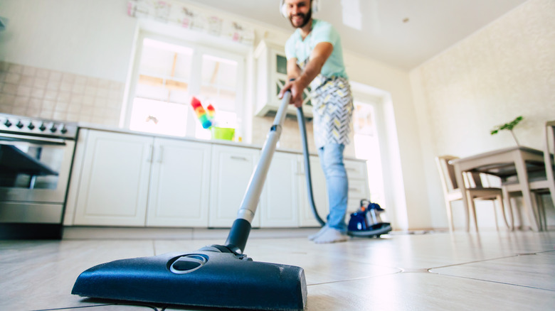 man vacuuming kitchen