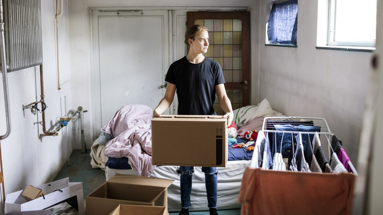man carrying box in cluttered basement