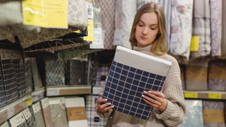 Woman holding set of flannel sheets at store