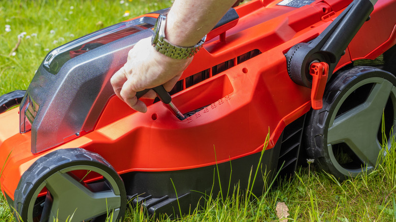 Closeup of a person adjusting the height setting on a lawn mower