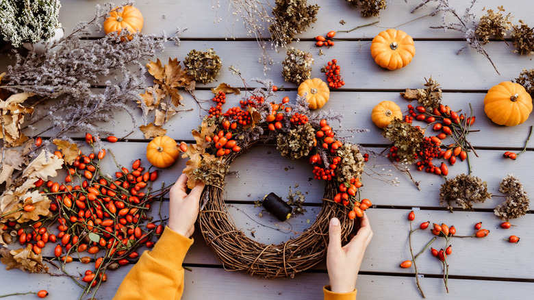 Closeup of a hand making a fall wreath with foliage