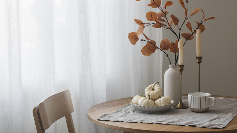 A table set with a vase filled with fall foliage bouquet