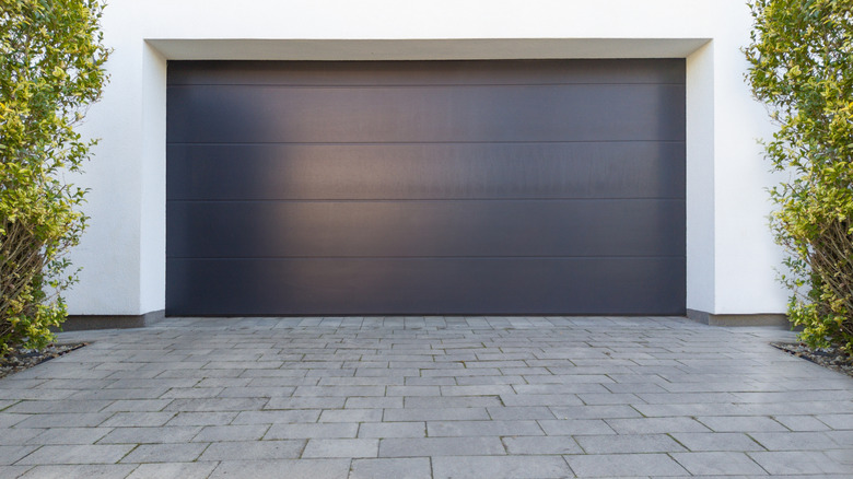 A gray garage door with paved driveway