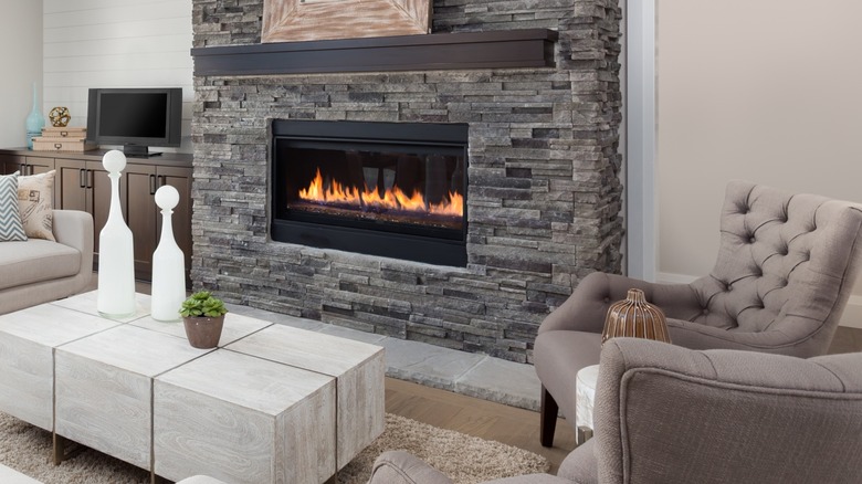 Lit gas fireplace inside a gray brick facade