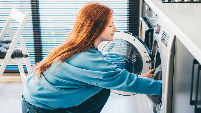 Woman putting laundry in washing machine