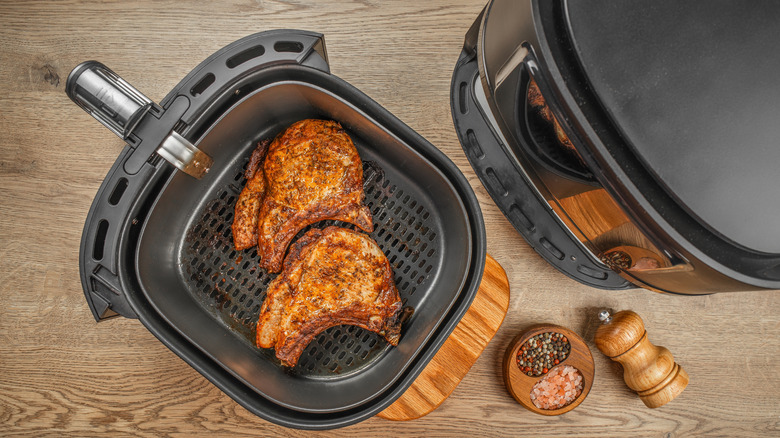 A top-down view of an air fryer with cooked food inside of it