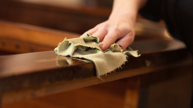 person wiping wood with cloth