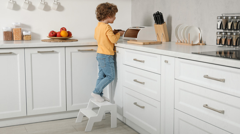 Small boy standing on a step stool in a kitchen