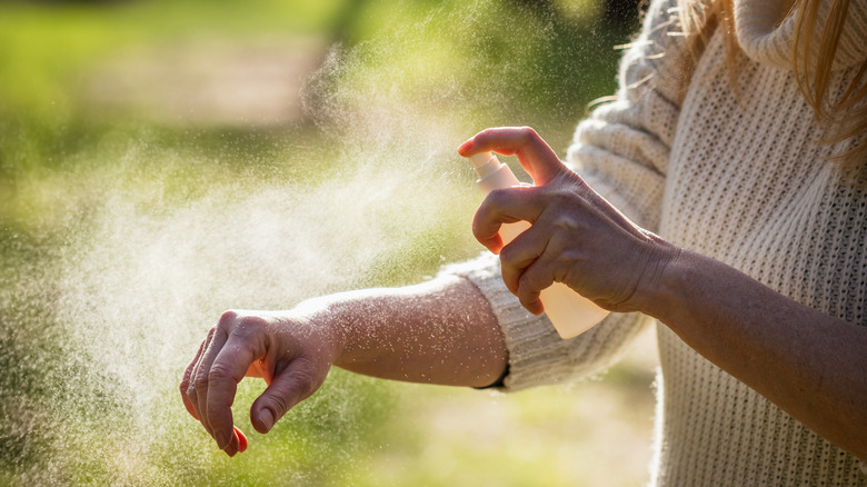 Person applying spray to arm