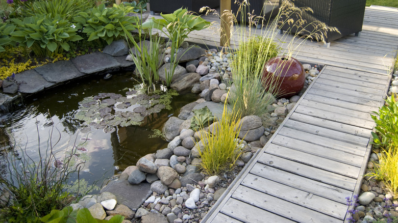 backyard pond surrounded by deck and stones