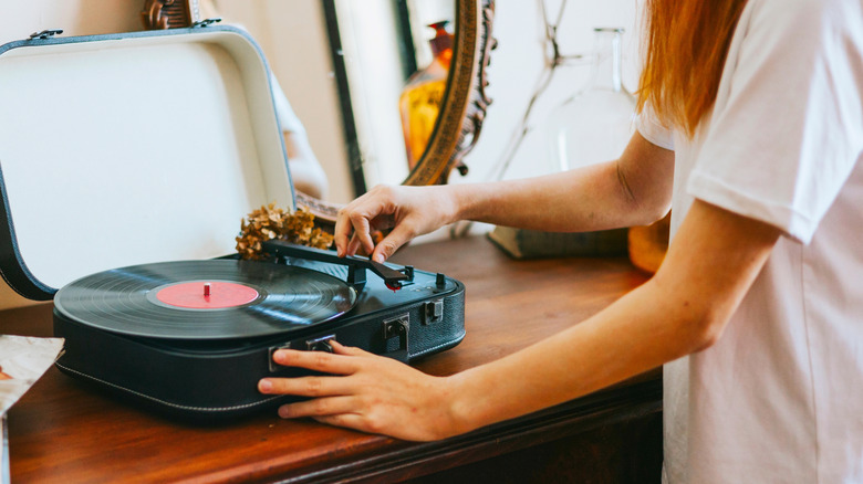 A girl playing a record on a suitcase record player