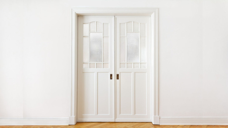 Dual white pocket doors on a blank wall.