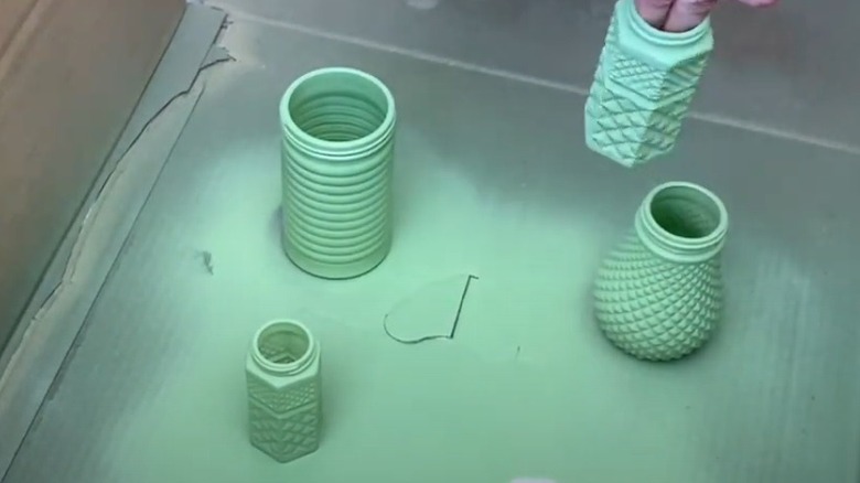 Fingers holding spray painted green dishware