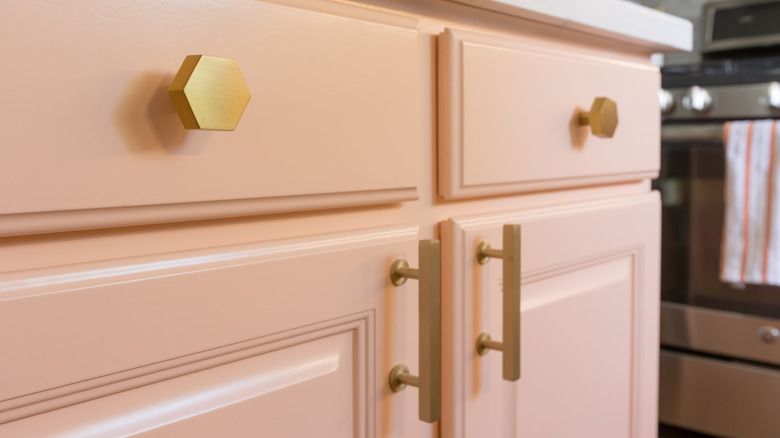 Peach kitchen cabinet with gold drawer pulls and cabinet handles