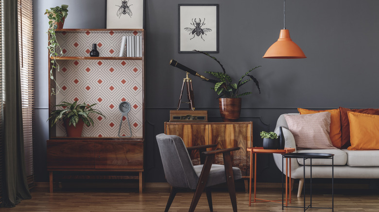 A dark gray living room with natural range wood furniture and orange accents.