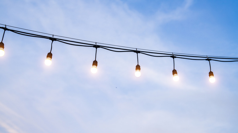 String lights are illuminated in front of a blue sky