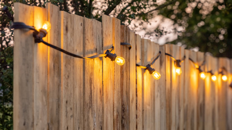 Warm-toned outdoor string lights on a fence