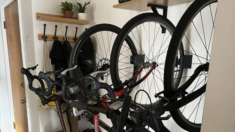 multiple bike stored on hooks vertically under stairs in home entryway