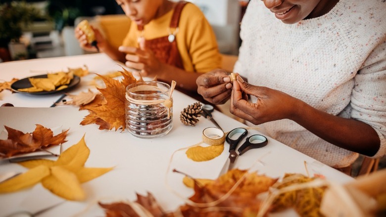 Two people creating fall craft with leaves and string