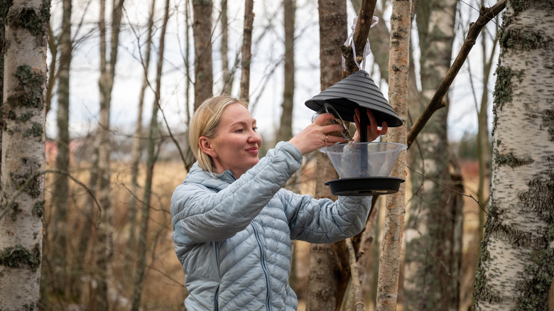 person refilling bird feeder