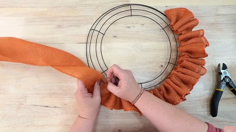 Adding orange burlap to cut wire frame to create ruffled pumpkin burlap wreath.